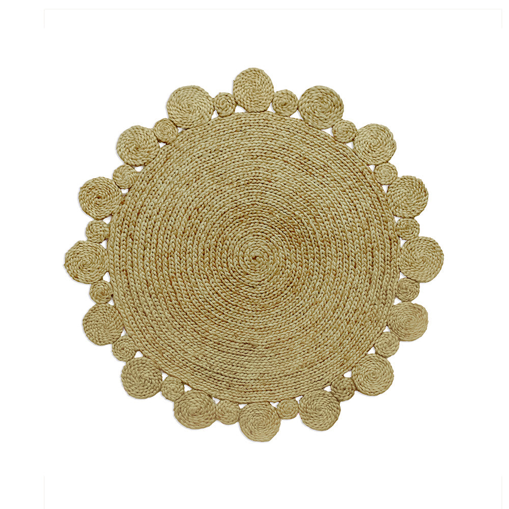 A round, beige-colored jute rug with scalloped edges and various circular design elements, handcrafted and displayed against a white background.