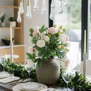 Decorative table setting with a vase of flowers and candles in a home interior.