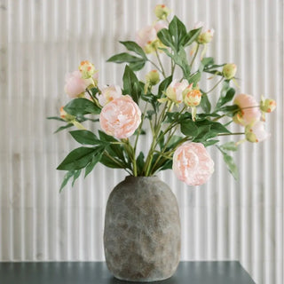 Vase with pink flowers and green leaves on a neutral background