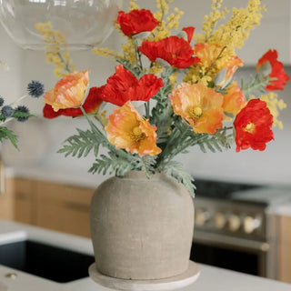 Vase with red and orange flowers on a kitchen counter
