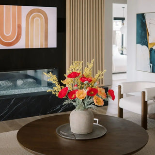 Decorative flowers in a pot on a coffee table in a living room setting.