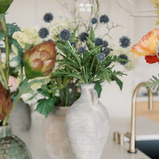 Decorative floral arrangement with a white vase on a kitchen counter.