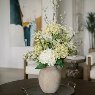 Floral arrangement in a textured vase on a table with a blurred indoor setting