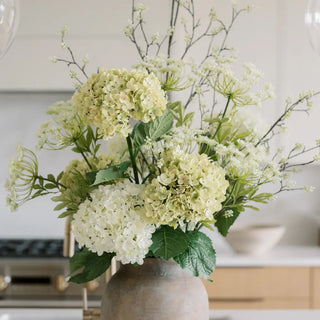 Bouquet of white and green flowers in a vase on a kitchen counter.