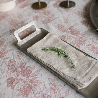 Chic serving tray with handles from CG Hunter, adorned with linen napkins and a sprig of rosemary, presented on a floral tablecloth.