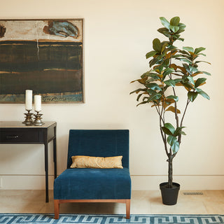 7' Artificial Magnolia Tree by CG Hunter positioned elegantly beside a stylish blue chair in a contemporary living space, enhancing the luxury aesthetic.