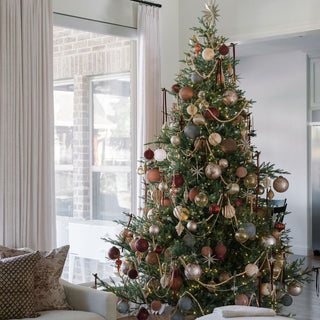 Luxurious holiday tree adorned with various decorations, including the 4" Mercury Ribbed Glass Antique Gold Ornament by CG Hunter, radiating elegance and festive charm in a beautifully styled living space.