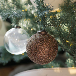 Chic 4-inch clear glass ornament by CG Hunter, featured alongside a textured dark ornament, enhancing the dazzling decor of a Christmas tree.