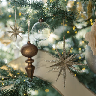 Close-up of luxurious holiday ornaments including shimmering star shapes and matte glass finials, showcasing the assorted neutral palette from CG Hunter.