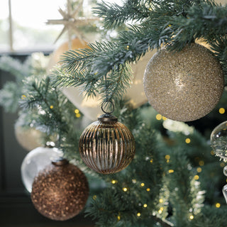 An elegant arrangement of 4-inch beaded cream glass ornaments alongside glamorous decorations on a holiday tree, creating a sophisticated look, by CG Hunter.