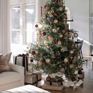 Elegant holiday scene featuring a beautifully decorated Christmas tree adorned with Slate Blue glass ornaments by CG Hunter, showcasing a luxurious artistic charm.