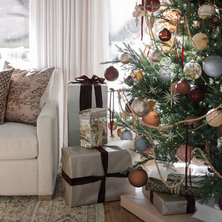Festive living room adorned with the 4" Textured Cinnamon Glass Ornament by CG Hunter, beautifully complemented by wrapped gifts beneath a stylishly decorated Christmas tree.