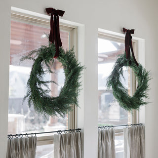 Detailed view of a single 30" Faux Evergreen Cedar Wreath from CG Hunter, adorned with a rich ribbon, elegantly displayed in a modern interior setting.