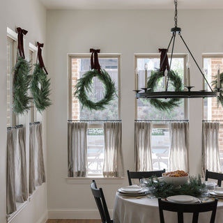 A stunning view of a dining area with multiple 30" Faux Evergreen Cedar Wreaths from CG Hunter hanging in elegant harmony, enhancing the festive spirit of the space.