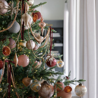 Exquisite holiday decorations featuring 5-inch Mercury Marble Glass Ornaments by CG Hunter, elegantly showcased on a beautifully adorned Christmas tree.