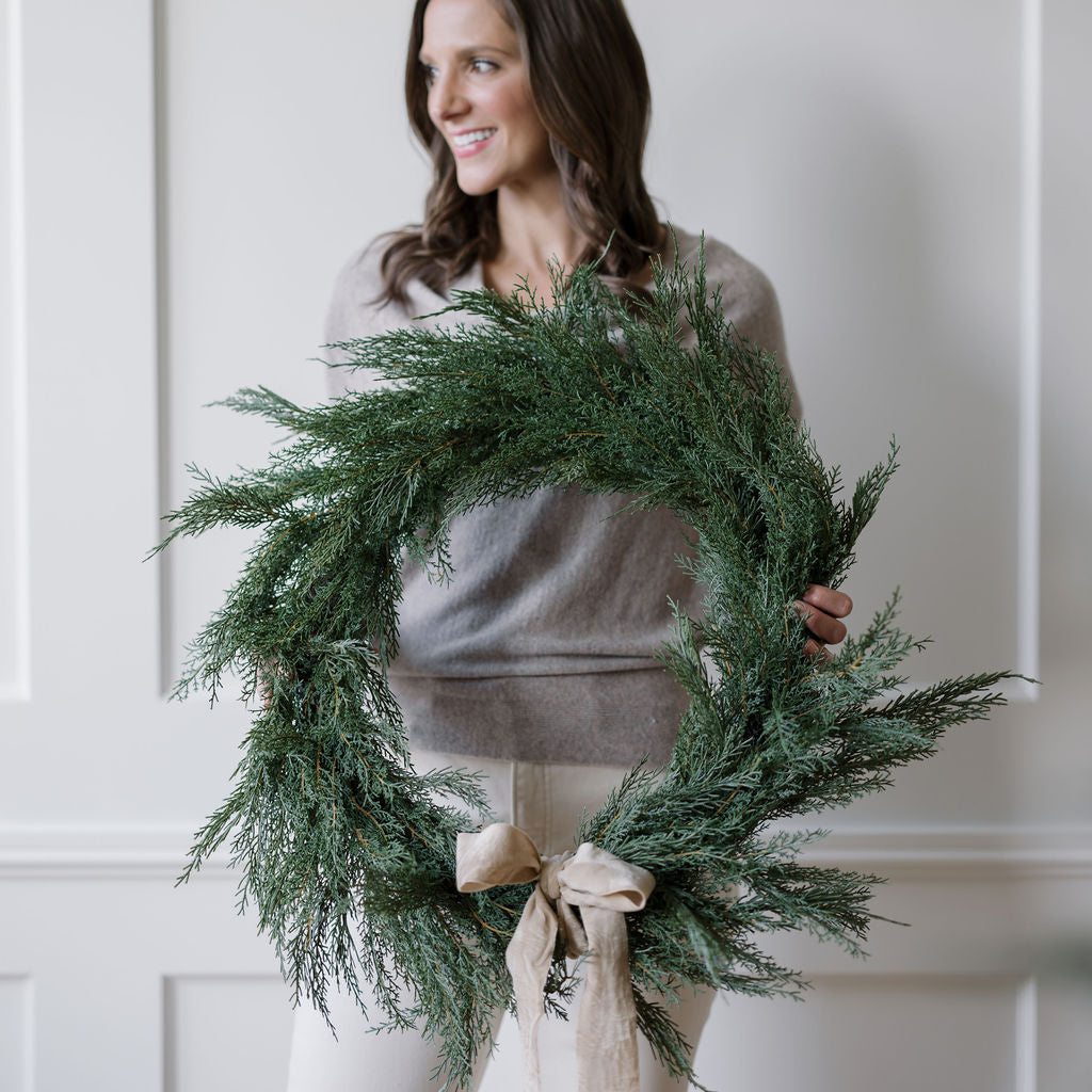 Jamie holding 30" Lifelike Cedar Wreath with wide velvet ribbon