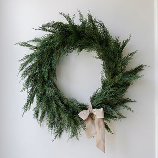 Beautifully arranged 30" Faux Evergreen Cedar Wreath by CG Hunter, elegantly displayed on a wall with a soft background.