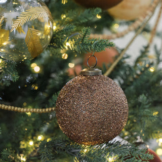 Beautifully designed 4" Beaded Antique Bronze Glass Ornament by CG Hunter, delicately displayed on a decorated Christmas tree, featuring a shimmering bronze surface.
