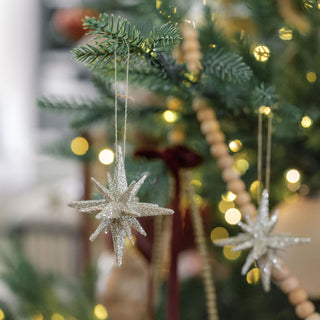 A pair of 2.75" Gold Glitter Starburst Ornaments by CG Hunter, sparkling elegantly in a beautifully styled Christmas tree setting.