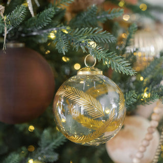 Sophisticated 3" Artisan Glass Gold Etched Leaf Ornament by CG Hunter, artfully hanging from a Christmas tree surrounded by luxurious ornaments and golden accents.