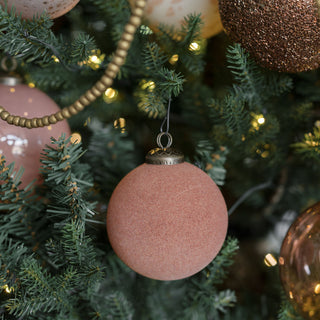 A close-up of a 3" Flocked Vintage Rose Glass Ornament by CG Hunter, nestled among twinkling lights and complementary ornaments, exuding a rich and stylish holiday charm.