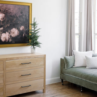 Elegant living room featuring a 24" / 2’ Artificial Evergreen Cedar Tree Set by CG Hunter, artistically placed next to a vintage painting and modern furnishings.