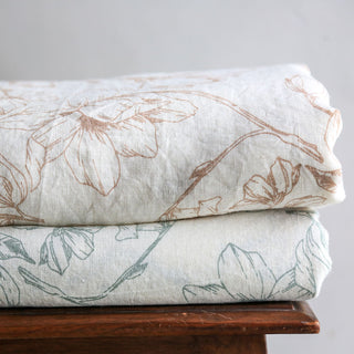 Artisan-crafted CG Hunter Grey and Green Lilies Linen Tablecloth featured alongside a complementary soft linen, highlighting the sophisticated floral designs.