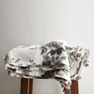 Stylish display of the CG Hunter Handcrafted Linen Eggplant and Grey Roses Tablecloth folded neatly, featuring intricate grey rose designs that embody sophistication.