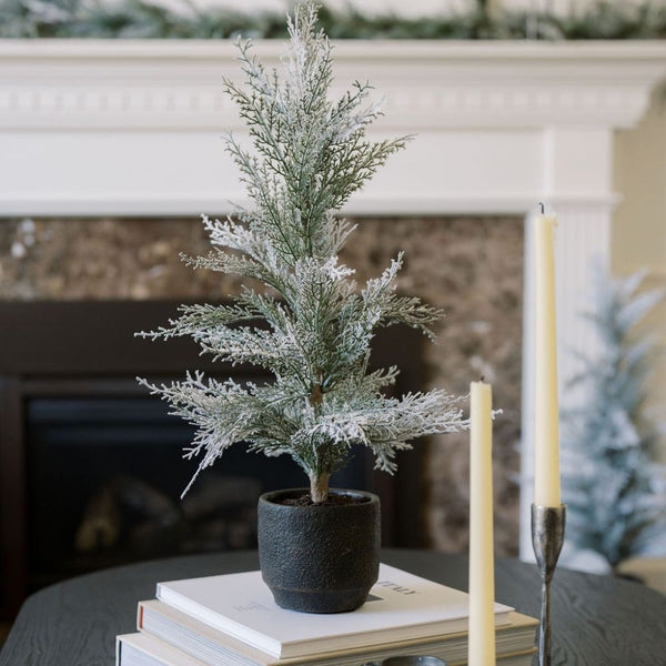 Elegant 2' Flocked Cedar Tree by CG Hunter displayed in a stylish black pot, showcasing its lifelike snowy branches, perfect for enhancing holiday decor in any luxurious setting.