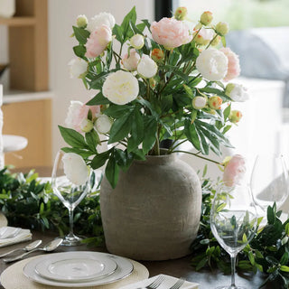Floral arrangement in a vase on a table with plates and glasses