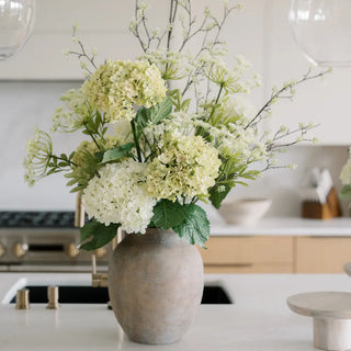 Vase with white and green flowers on a kitchen counter
