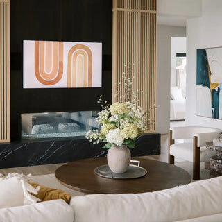 Modern living room with a white sofa, round wooden coffee table, and abstract wall art.