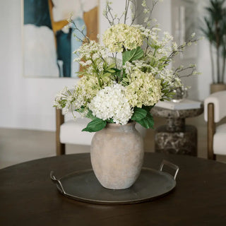 Floral arrangement in a textured vase on a table in a room setting