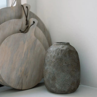 Three stone-like vases of varying sizes on a white surface with a light gray background.