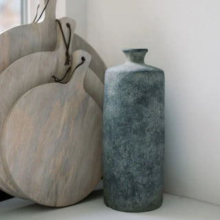 Set of wooden cutting boards and a textured blue vase on a white surface.