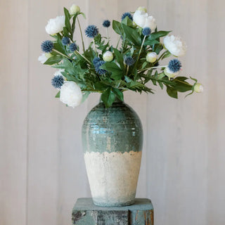 Decorative vase with a bouquet of flowers on a wooden stand against a plain background