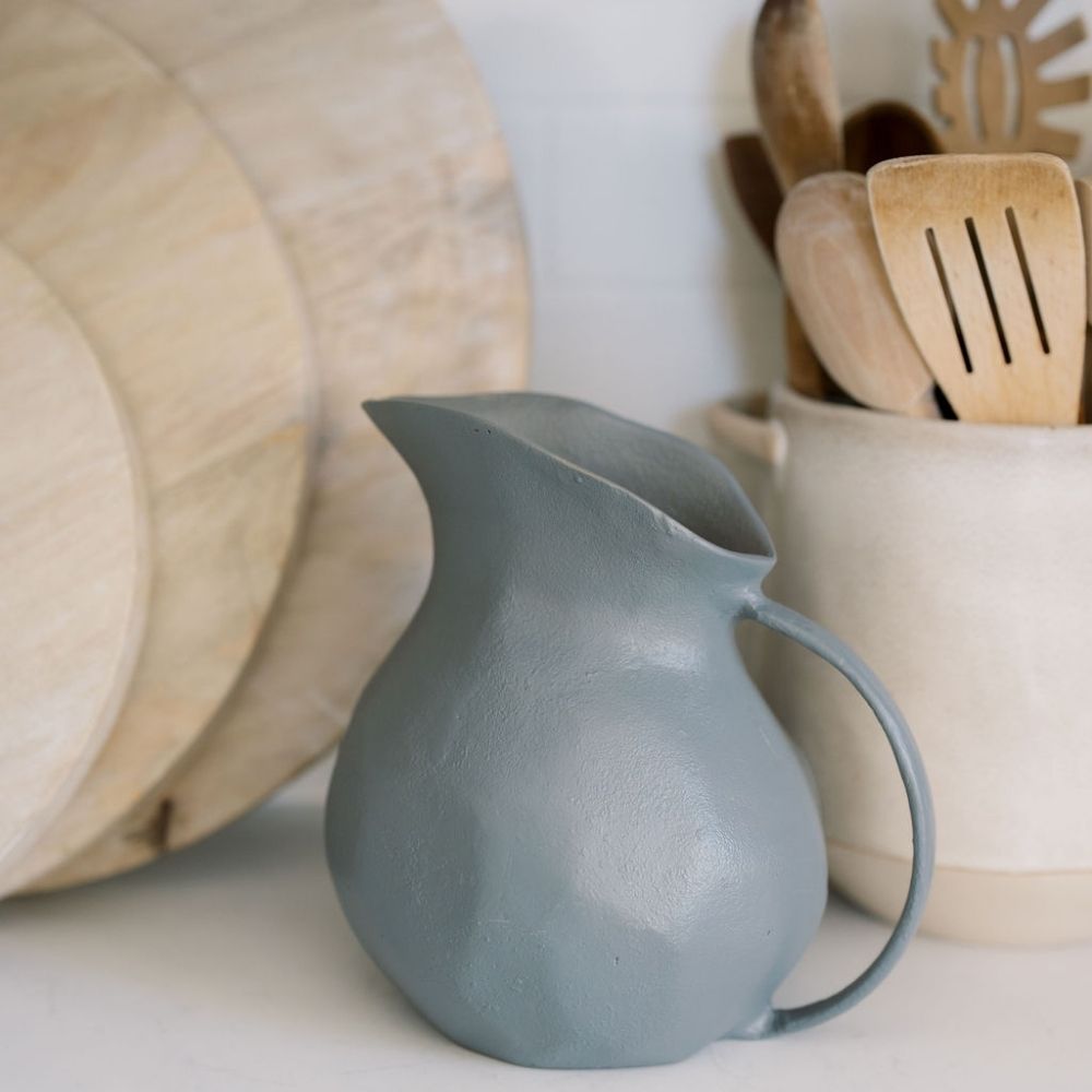 Chic display of the 8.5" Warm Grey Aluminum Vase with Handle by CG Hunter, complementing wooden kitchen tools in a refined interior.
