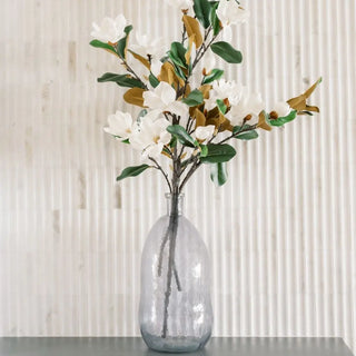 Clear glass vase with artificial flowers on a neutral background