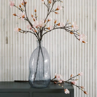 Decorative vase with pink flowers on a dark surface against a light background