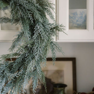 Stunning view of the 30" Flocked Cedar Wreath by CG Hunter, featuring lush, snow-dusted cedar foliage, gracefully hanging in a stylish kitchen setting, perfect for seasonal elegance.