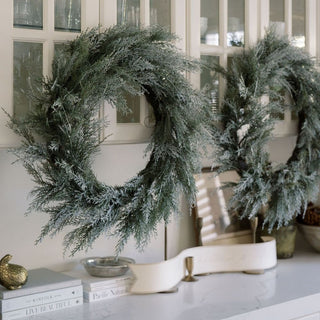Elegant 30" Flocked Cedar Wreath by CG Hunter displayed in a luxurious home setting, showcasing its lush, snow-dusted cedar branches.