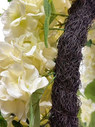 White flowers with a textured brown vine against a blurred floral background