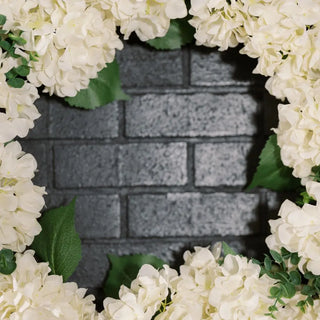 White flowers arranged in a circular pattern with a gray brick wall in the center.