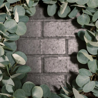 Circular wreath made of green leaves with a blurred brick wall background