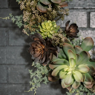 Arrangement of succulents and flowers against a brick wall.