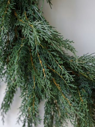 Close-up view of lifelike faux evergreen cedar branches, highlighting the intricate details of the 30" Faux Evergreen Cedar Wreath by CG Hunter.