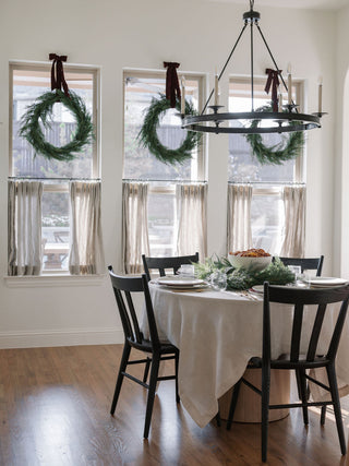 Stylish dining room setting featuring multiple 30" Faux Evergreen Cedar Wreaths by CG Hunter, harmoniously enhancing the festive atmosphere.