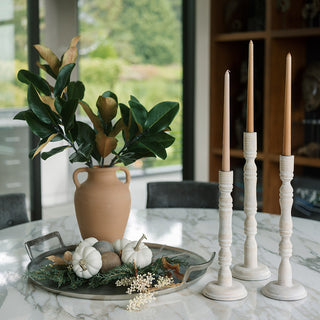 Elegant white mango wood tapered candle holders by CG Hunter displayed on a marble dining table with decorative elements, showcasing a luxurious home decor style.