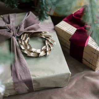 Close-up of a 5-inch brass iron wreath ornament on a beautifully wrapped gift, radiating luxury and elegance. Crafted by CG Hunter, ideal for sophisticated holiday decorations.