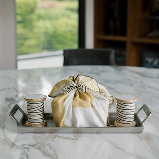 Elegant serving tray with handles by CG Hunter, featuring a pewter finish, showcasing wrapped items and decorative spools on a marble table.